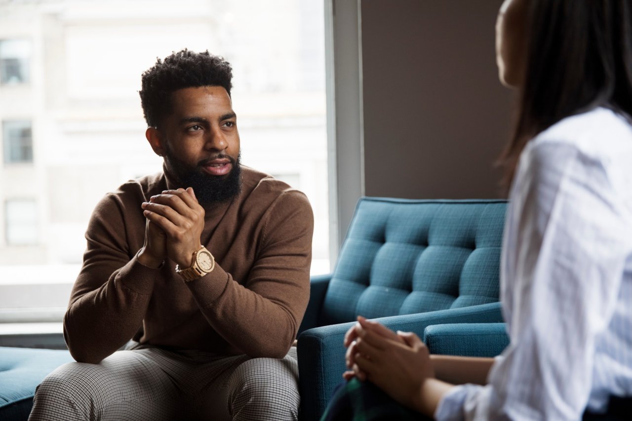Man sat on chair talking to mental health professional.