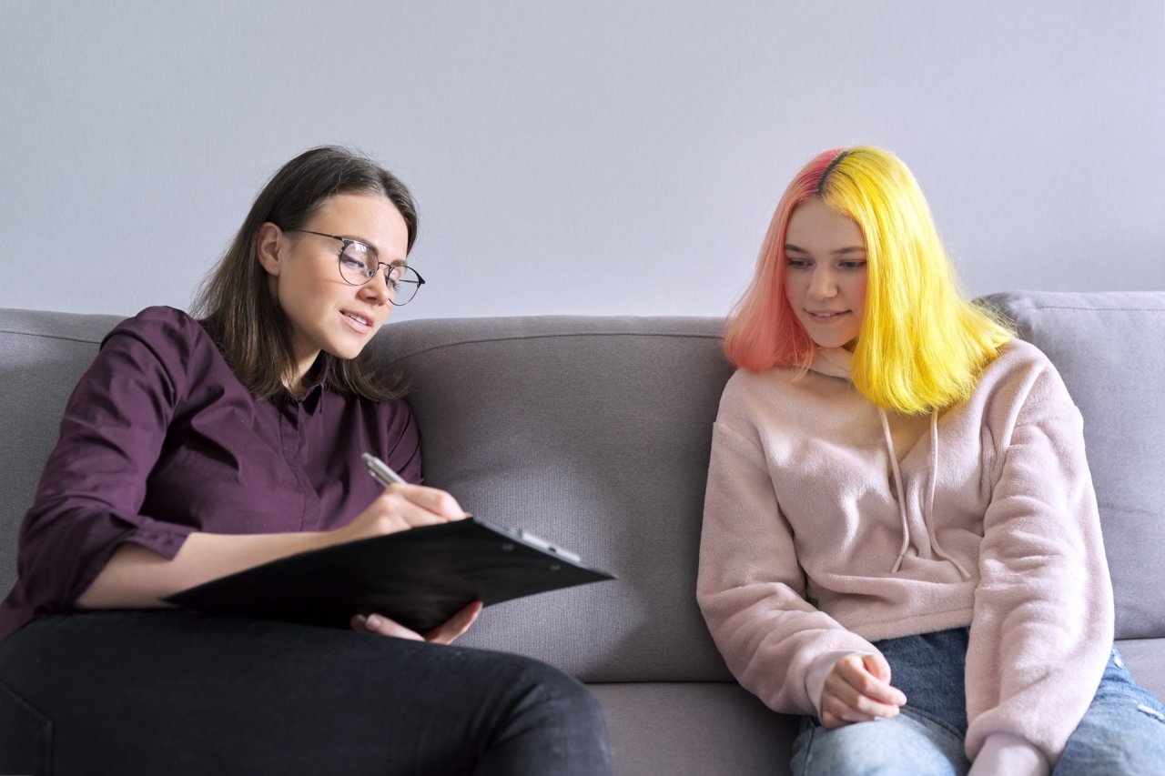 Young woman sat on sofa with a counsellor.
